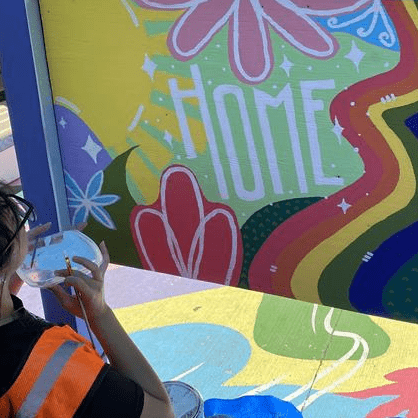 Young person painting sign that says "Home"