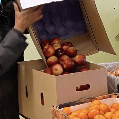 box of apples being poured into container of food program table
