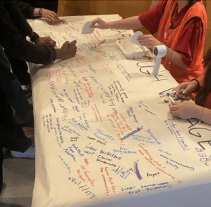people writing together on a paper at a community meeting